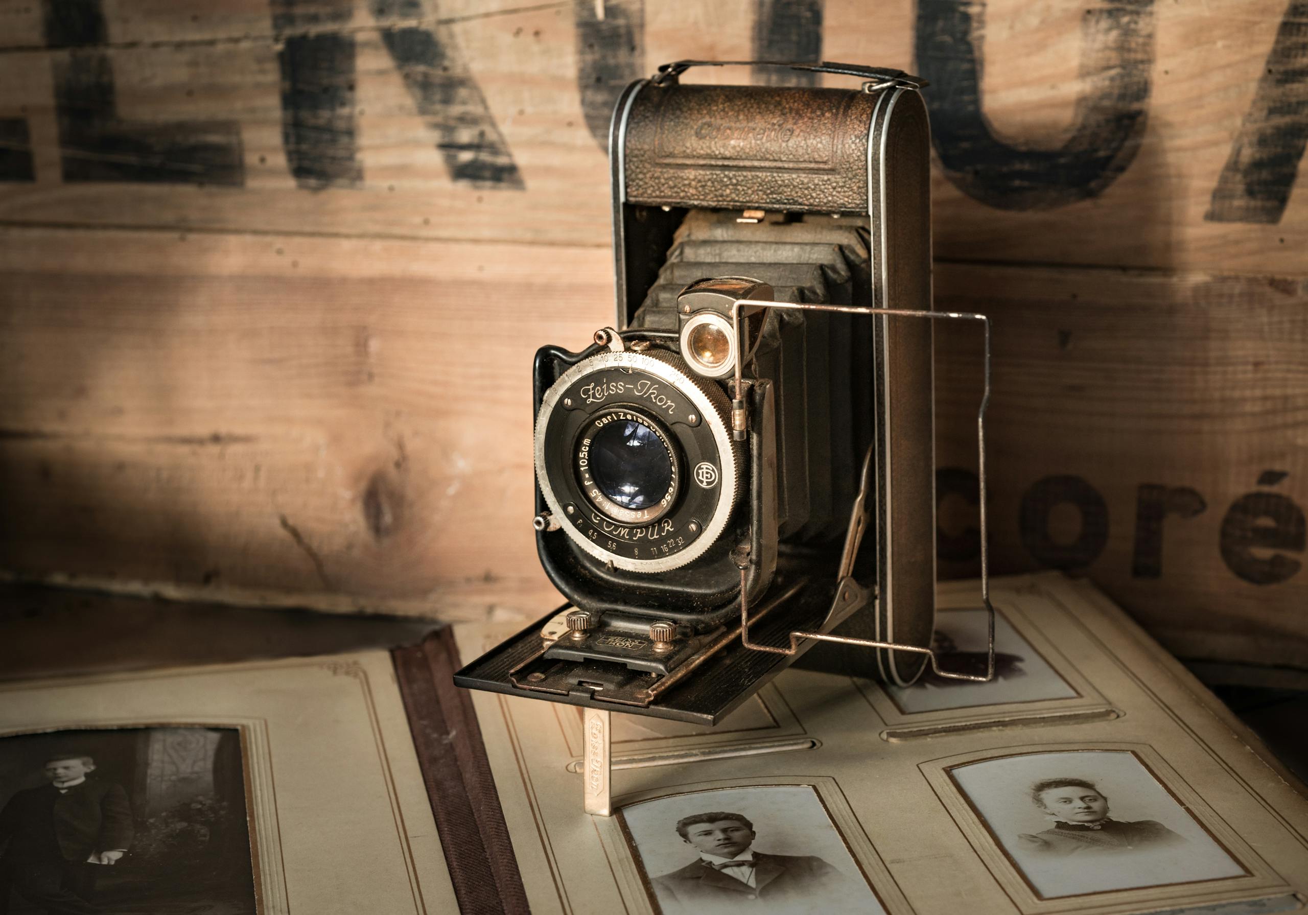 A classic Zeiss Ikon camera resting on an antique photo album highlighting nostalgia.